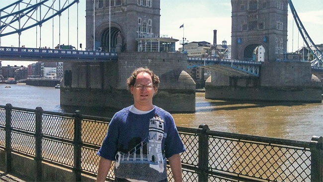Sam Barksy vor der Tower Bridge, mit einem Pulli mit Tower Bridge vorne drauf.